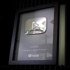 Silver play button in a framed plaque with text: 